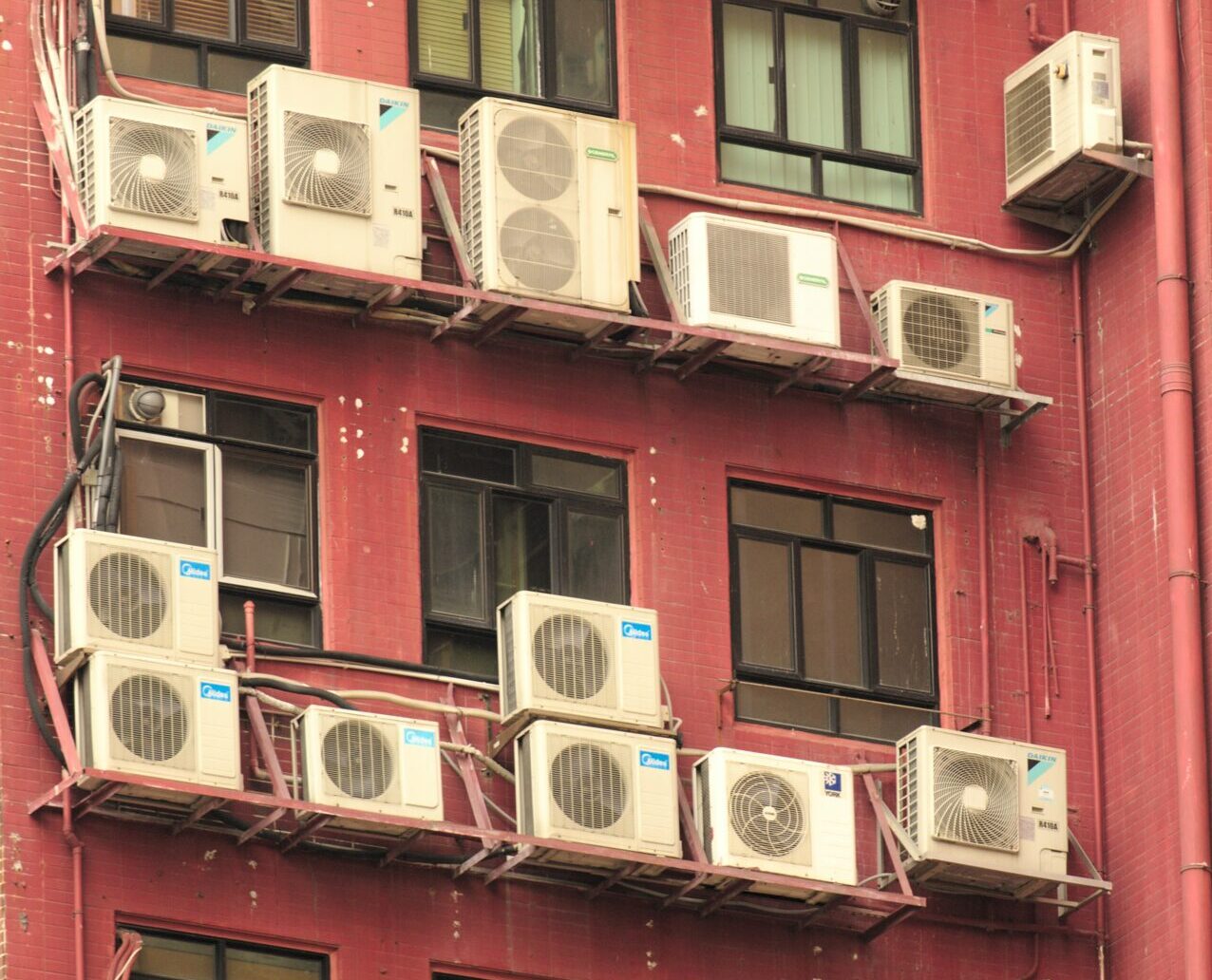outside air conditioners on red building